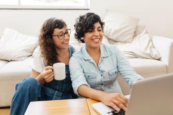 two women smiling at laptop