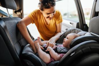 Woman buckling baby into a car seat