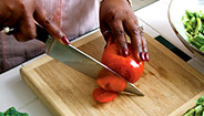 Mujer rebanando verduras en una tabla de picar Mujer rebanando verduras en una tabla de picar