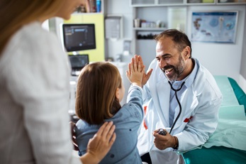 male doctor giving girl patient a high five