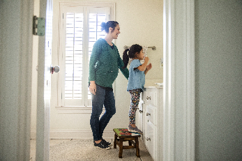 mother helping child brush teeth