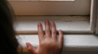 Niño con las manos en el alféizar de una ventana