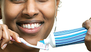 Mujer sonriendo con cepillo de dientes y pasta dentífrica