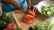 Mujer rebanando verduras en una tabla de picar