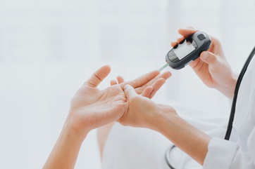 médico usando un glucómetro en el paciente