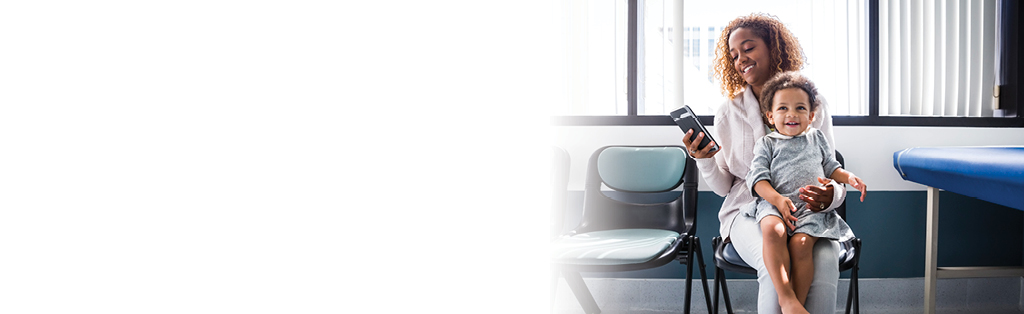 mujer que sostiene a un niño y mira un teléfono celular