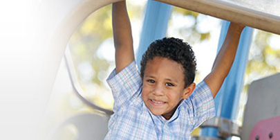 smiling boy hanging on playground equipment