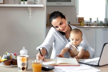 madre sosteniendo al bebé y escribiendo en el cuaderno