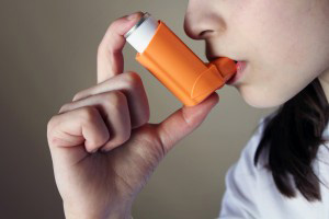 Person using asthma inhaler.