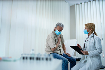 masked patient talking to doctor